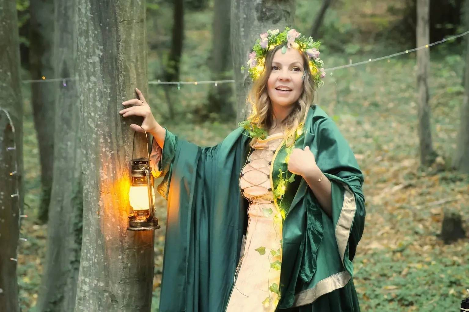 Marion en nymphe des bois, couronne de fleurs lumineuse et lanterne à la main, dans la forêt