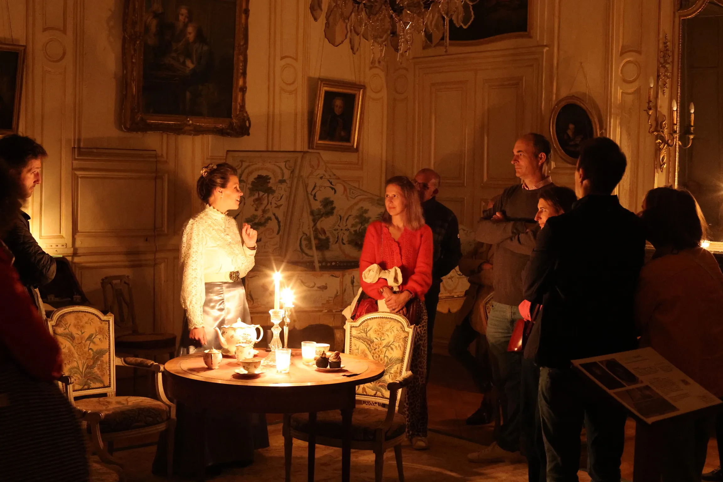 Une comédienne en costume d’époque raconte l’histoire du château aux visiteurs, à la lueur des bougies