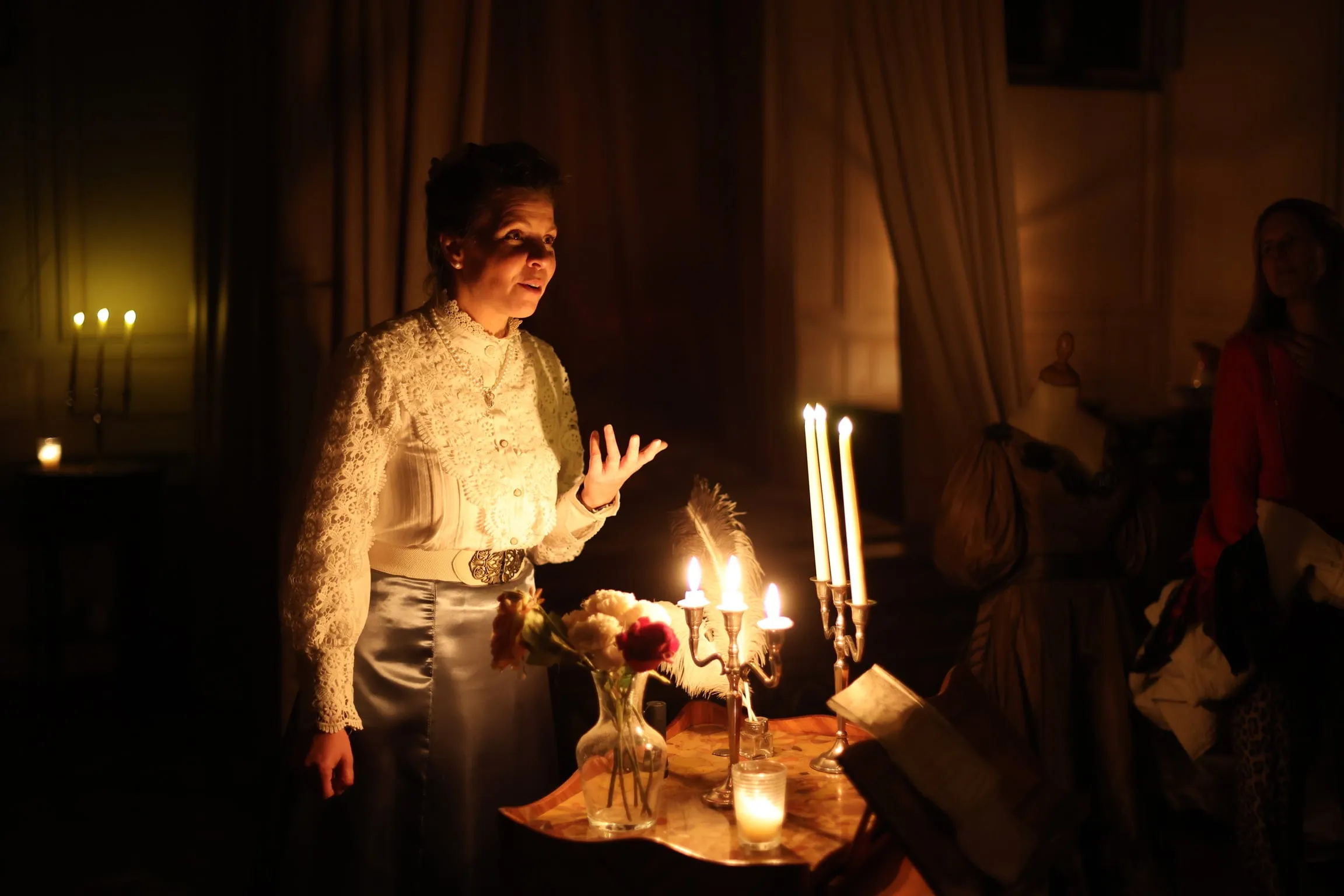 Une comédienne en robe de dentelle raconte la visite à la lueur des chandeliers